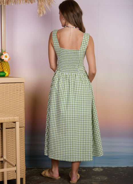 Woman wearing a green checkered dress standing by a beach with a blurred background