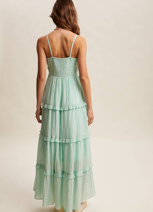 Woman wearing a mint green tiered dress on a beige background