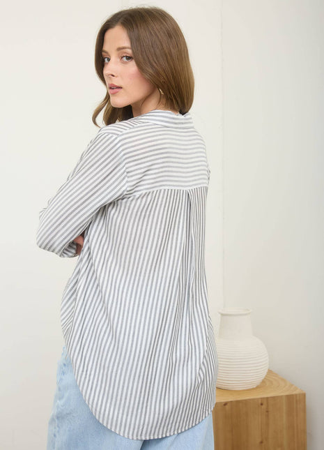 Woman wearing a striped shirt and light blue jeans against a white background