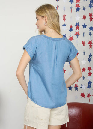 Woman wearing a blue top and white shorts against a star-patterned wall.