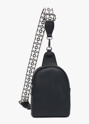 A small black leather crossbody bag with a wide, patterned black and white strap featuring a repeating floral motif and silver-tone hardware.