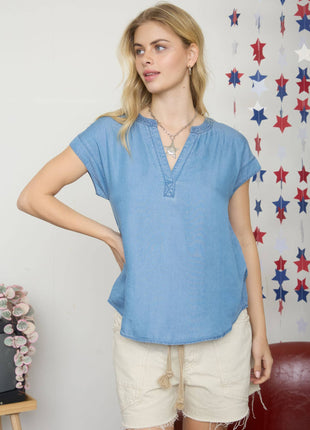 Woman wearing a blue top and beige shorts in front of a decorative star-patterned wall.