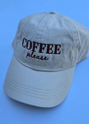 A light gray cotton baseball cap with 'COFFEE please' embroidered on the front, set against a solid blue background.