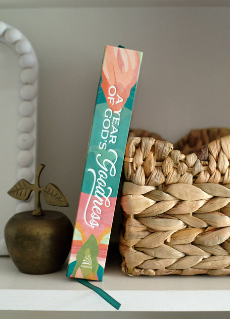 Colorful bookend with 'A Year of God's Goodness' text on a shelf with decorative items.