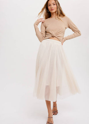 Woman wearing a beige top and white tulle skirt on a white background