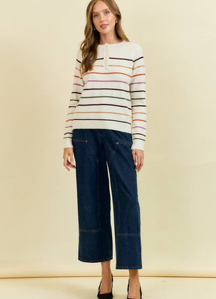 Woman wearing a striped sweater and wide-leg jeans against a beige background