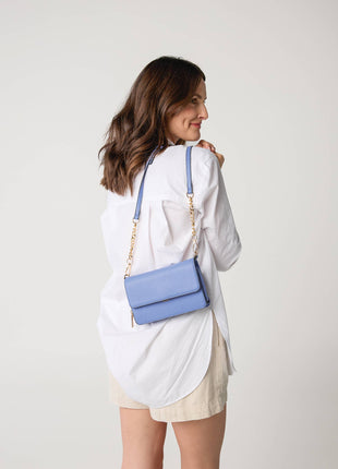 Woman carrying a blue handbag on a plain background