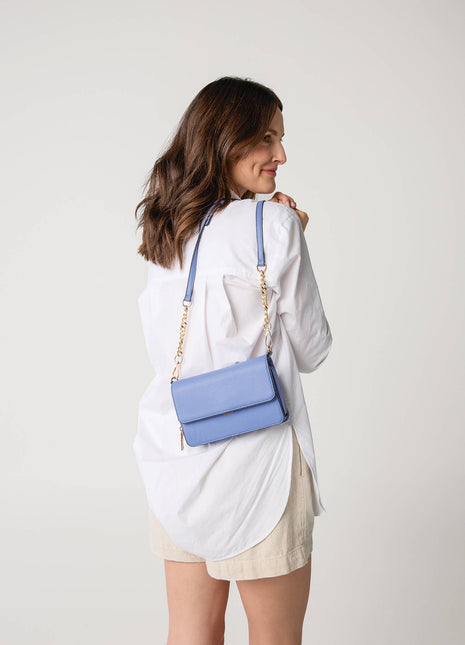Woman carrying a blue handbag on a plain background