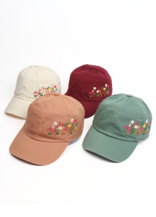 Four baseball caps in different colors with floral embroidery on a white background