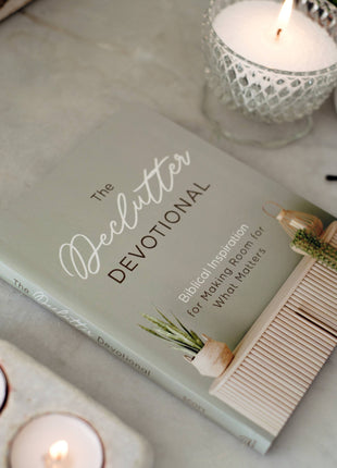 Book titled 'The Declutter Devotional' with candles on a surface