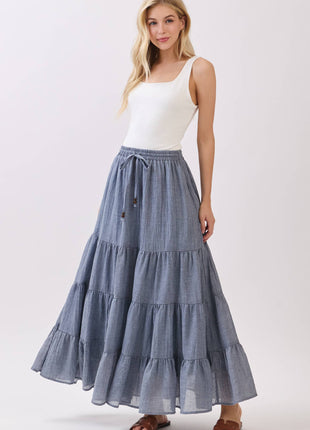 Woman wearing a white top and blue tiered skirt on a white background