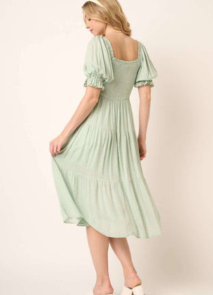 Woman wearing a light green dress with puffed sleeves on a plain background