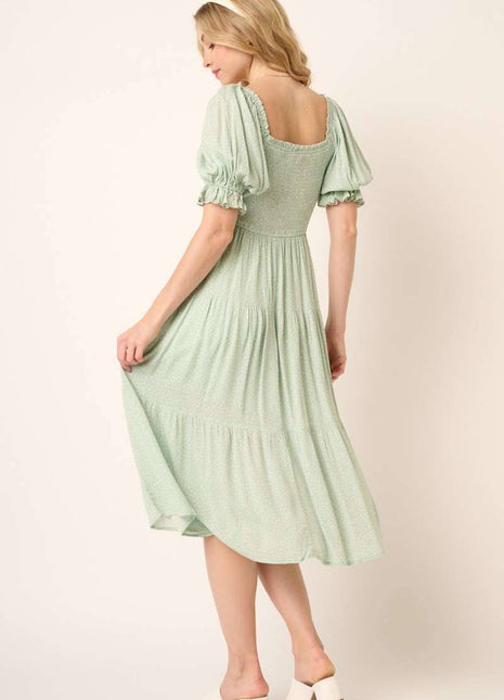 Woman wearing a light green dress with puffed sleeves on a plain background