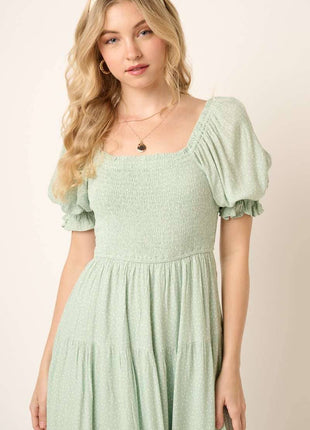Woman wearing a light green dress with puff sleeves against a beige background