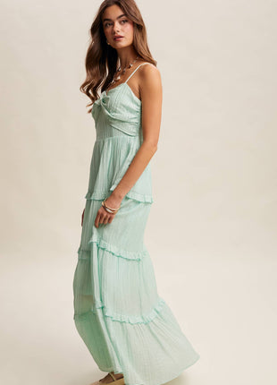 Woman wearing a light green dress with ruffled layers on a plain background