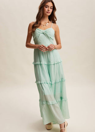 Woman wearing a mint green tiered dress on a plain background