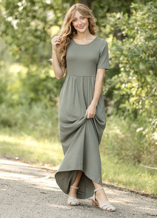 Woman wearing a green dress standing on a path with trees in the background