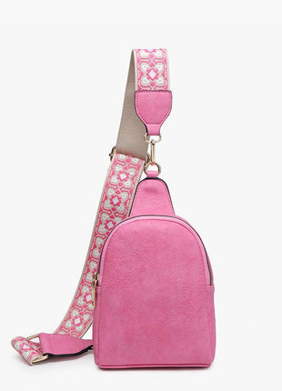Pink crossbody bag with a patterned strap on a white background