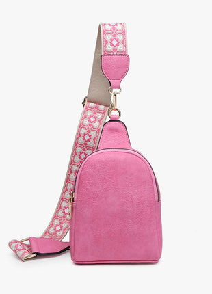 Pink crossbody bag with a patterned strap on a white background