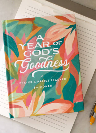 Colorful book titled 'A Year of God's Goodness' on a white surface with a pen.