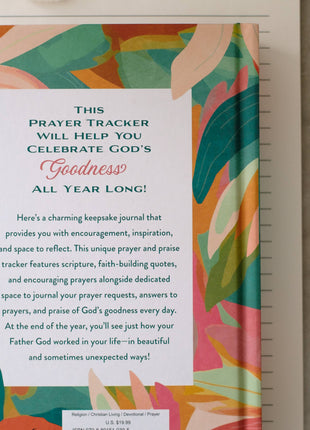 Prayer tracker journal with colorful cover and pen on a neutral background