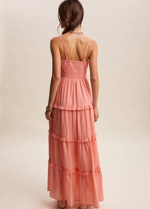 Woman wearing a coral tiered dress on a beige background