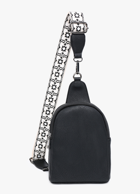 A black leather mini backpack with a wide, adjustable black and white patterned shoulder strap, shown against a plain white background.
