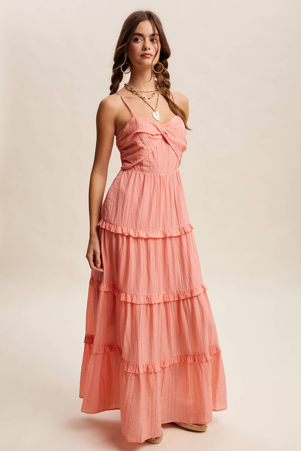 Woman wearing a coral pink dress with ruffled layers on a beige background