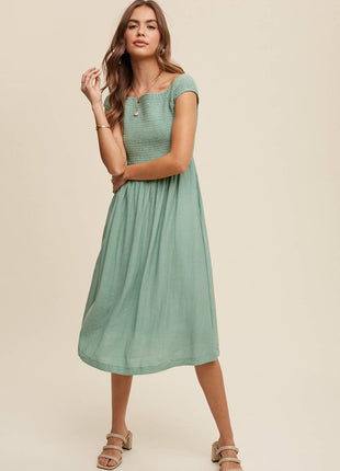 Woman wearing a green dress against a beige background