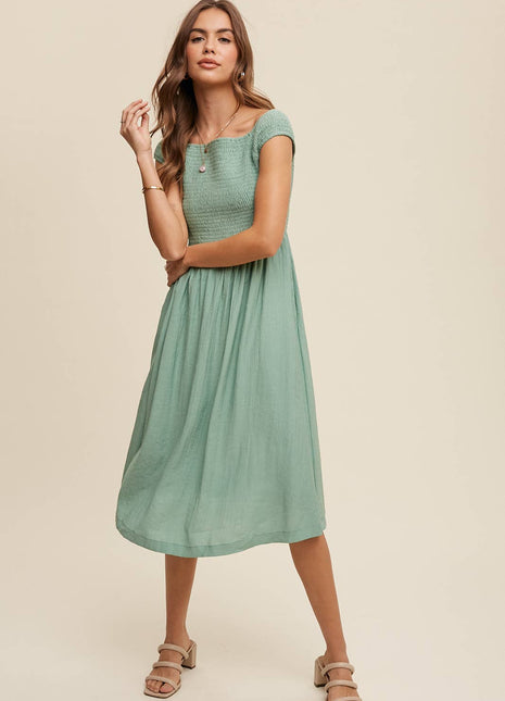 Woman wearing a green dress against a beige background