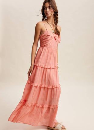 Woman wearing a coral tiered dress on a plain background