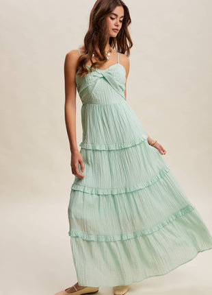 Woman wearing a mint green strapless, tiered dress on a beige background