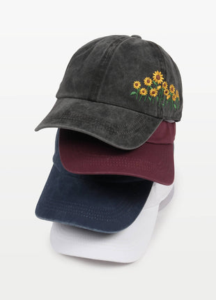 Stack of three baseball caps with floral embroidery on a white background
