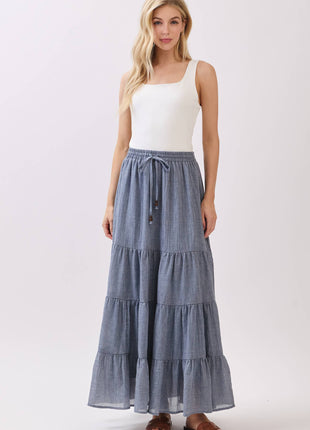 Woman wearing a white tank top and blue tiered skirt on a white background
