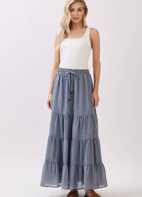 Woman wearing a white tank top and blue tiered skirt on a white background