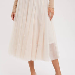 Person wearing a beige pleated skirt and brown top on a white background