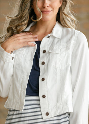 Woman wearing a white denim jacket with brown buttons indoors