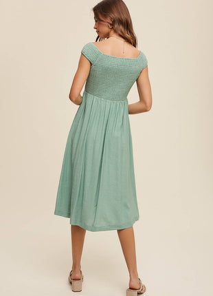 Woman wearing a green dress against a beige background