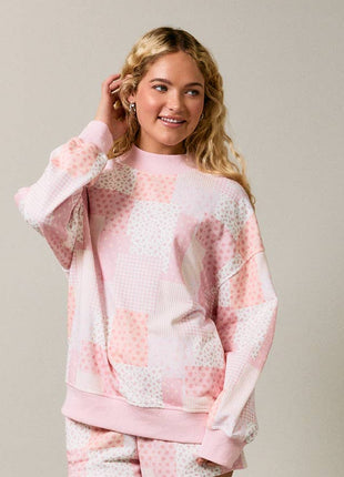 Woman wearing a pink and white patterned outfit on a plain background