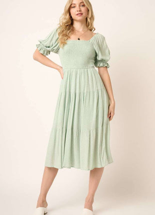 Woman wearing a light green dress with puff sleeves against a white background