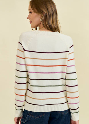 Woman wearing a white sweater with colorful stripes on a beige background