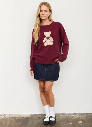 woman modeling burgundy sweater with teddy bear