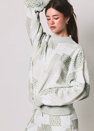 Woman wearing a light green patterned outfit on a plain background